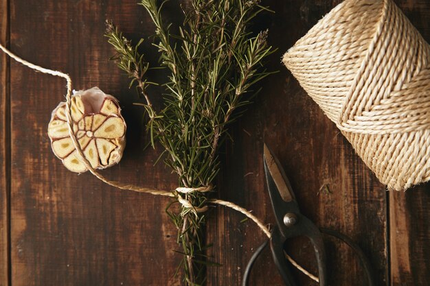 Old garden scissors, thick rope, garlic and rosemary on grunge wooden table. Top view.