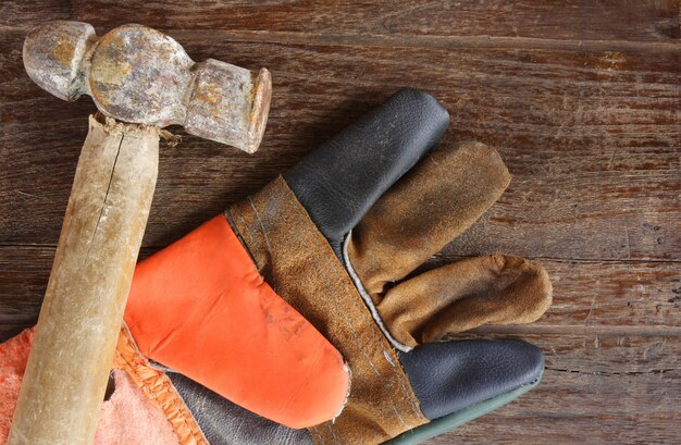 old Hammer and leather gloves on wood background