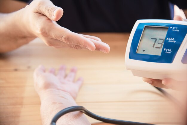 老婦人は血圧モニターの子供セットを使用して血圧をチェックされています