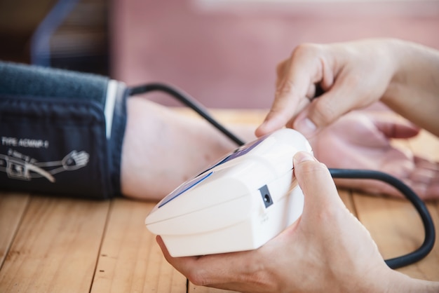 Vecchia signora viene controllata la pressione sanguigna utilizzando il set di bambini monitor di pressione sanguigna