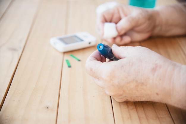 Old lady is testing blood sugar level using blood sugar test kid set 