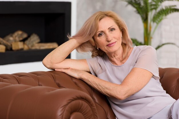 Old lady sitting on sofa and looking at camera