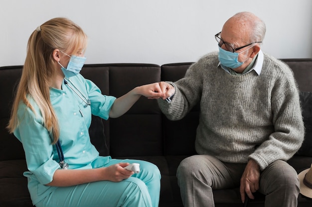 Old man fist bumping nurse in a nursing home