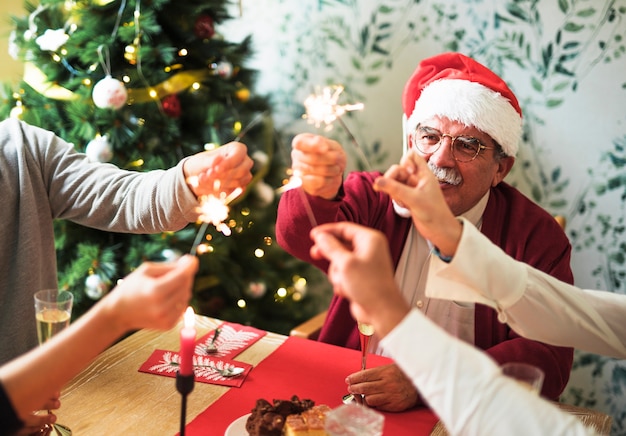 Free photo old man holding bengal fire at festive table with family