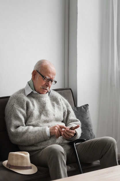 Бесплатное фото Старик в доме престарелых с помощью смартфона