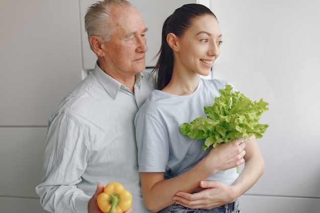 Old man in a kitchen with young granddaughter