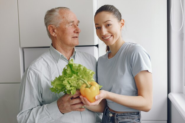 Old man in a kitchen with young granddaughter