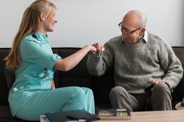 Old man in a nursing home fist bumping nurse