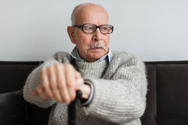 Free photo old man in a nursing home with glasses and cane