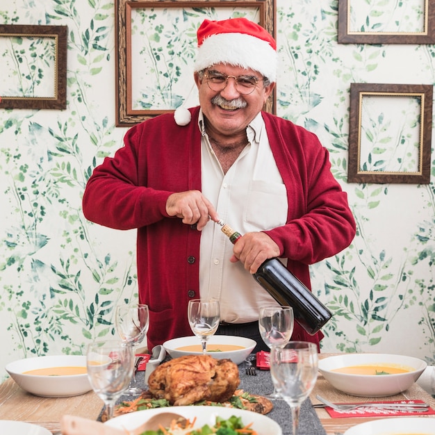 Бесплатное фото Старик открывал бутылку вина на праздничном столе