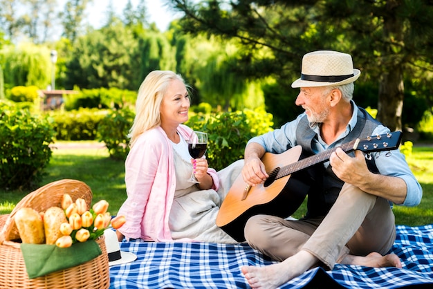 Foto gratuita uomo anziano che suona la chitarra per la sua donna