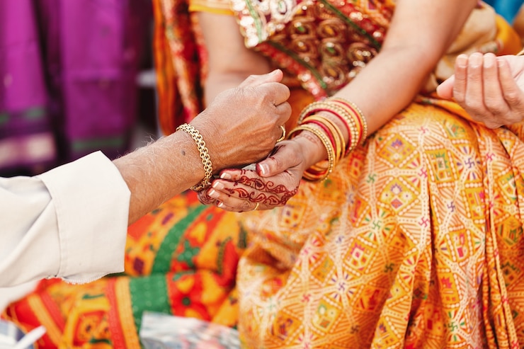 Free Photo old man pours something in the hands of indian woman dressed