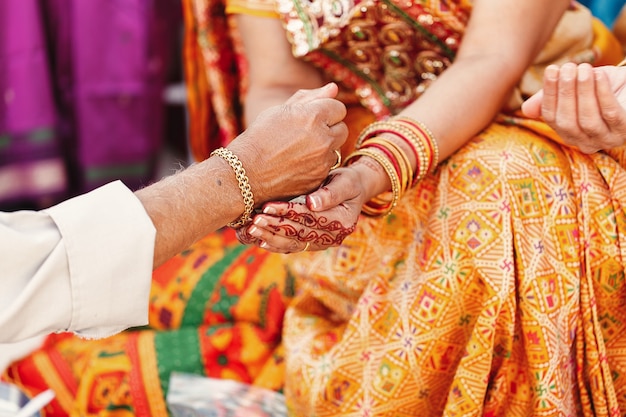 Old man pours something in the hands of Indian woman dressed