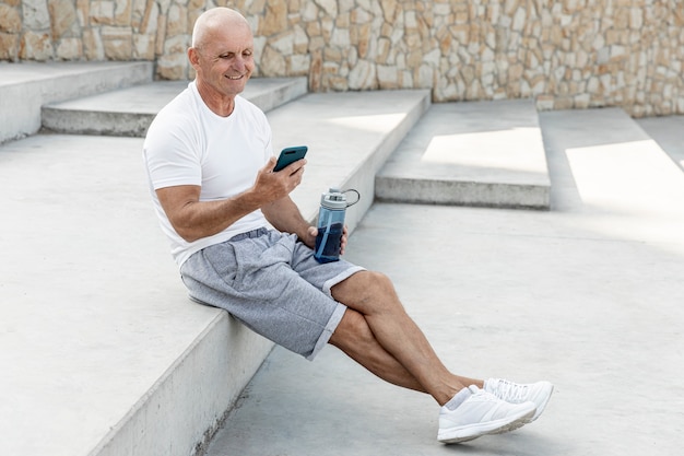 Old man resting looking at his phone full shot