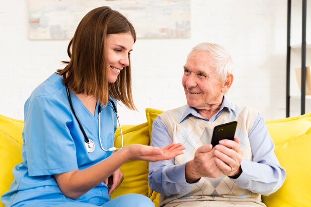Old man showing photos on phone to caregiver