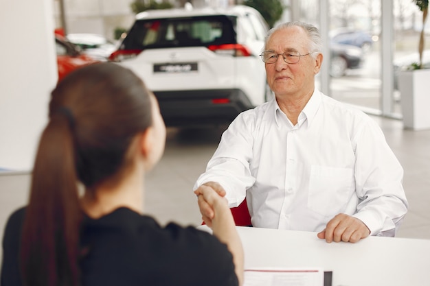 Old man sitting in a car salon and talking with manager