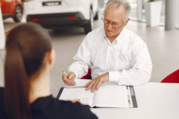 Old man sitting in a car salon and talking with manager