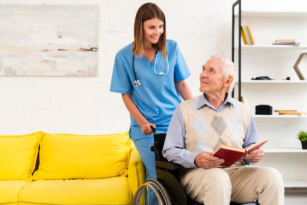 Old man sitting on wheelchair while talking to nurse