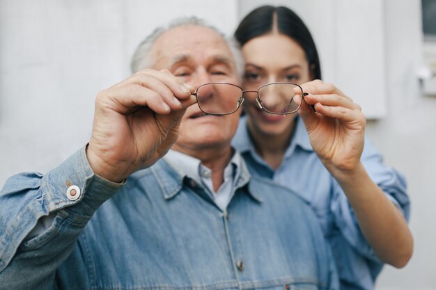 Old man standing on gray backround with his granddaughter