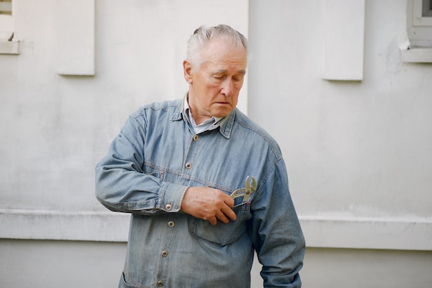 Free photo old man standing near building with a repair tools