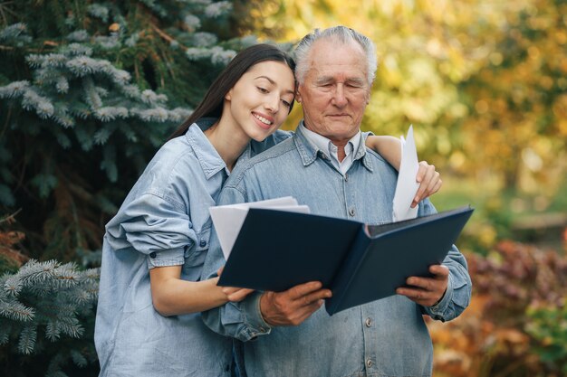 Old man standing in a park backround with his granddaughter