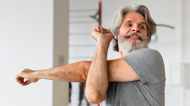 Old man stretching indoors