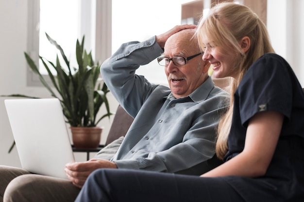 Old man video calling family from nursing home with nurse's help