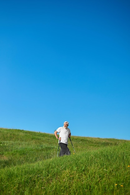 Old man walking on hills with tracking sticks
