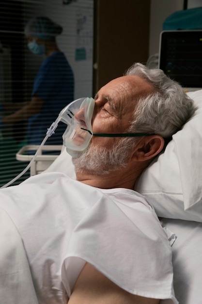 Старик с респиратором на больничной койке