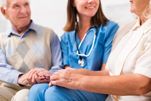 Old man and woman sitting on yellow sofa with nurse