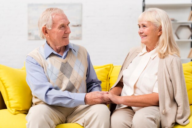 old man and woman talking on yellow sofa
