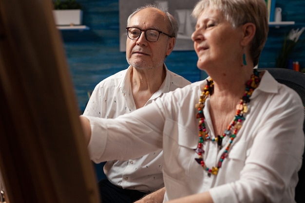 Free photo old man and woman working on drawing together