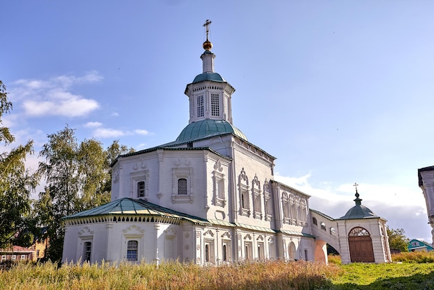 Old orthodox church at village. Summer view with floral meadow. Sunny day, blue sky with clouds.