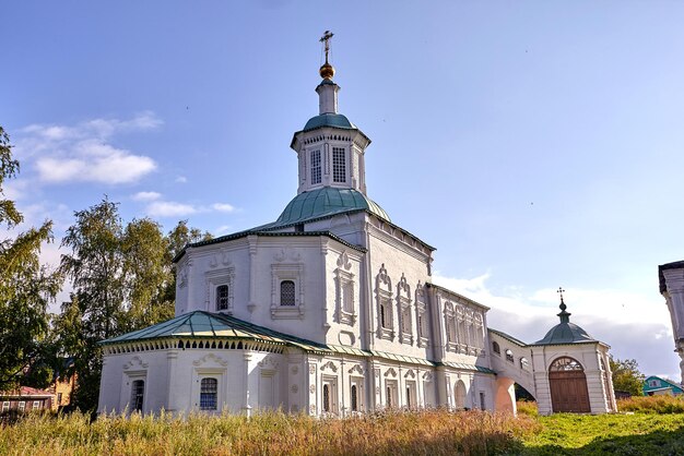 Старая православная церковь в деревне. Летний вид с цветочным лугом. Солнечный день, голубое небо с облаками.