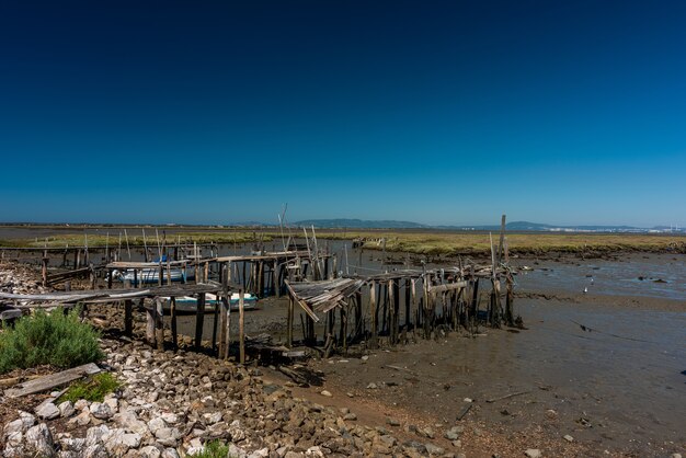 Cais Palafitico da Carrasqueira, 포르투갈의 햇빛 아래 해안에 오래 된 파괴 나무 갑판