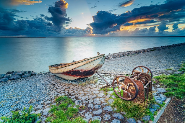 Old rusty fishing boat on the slope along the shore of the lake