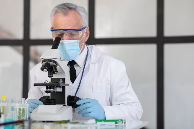 Old scientist working with microscope