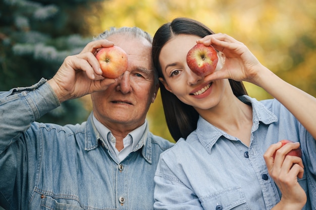 Old senior standing in a summer garden with apples