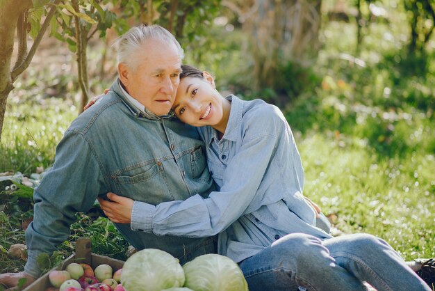 Old senior standing in a summer garden with harvest