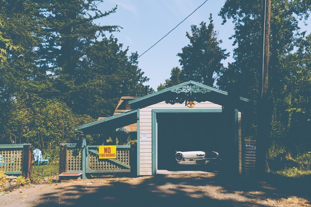 Old vintage car parked in a small garage next to a sign on a fence