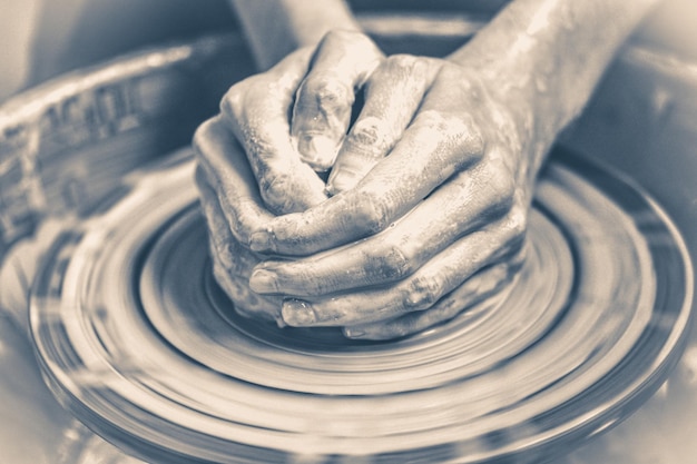 古い​ビンテージ​写真​。​一緒​に​折りたたまれた​マスター​陶芸家​は​、​ろ​くろ​に​粘土​製品​を​彫刻します​。​粘土​で​汚れて​濡れた​手​の​皮膚