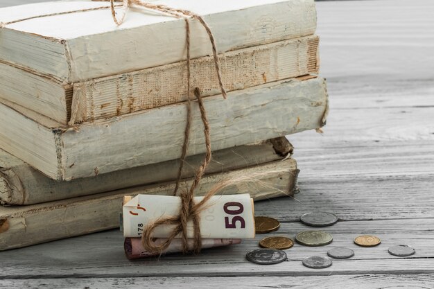 お金と木製の背景上のコインの古い白い本