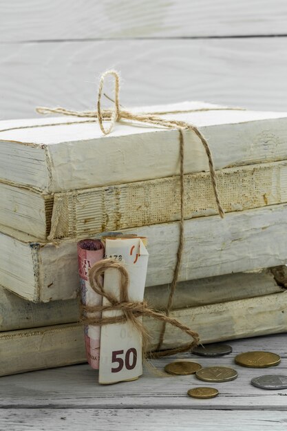 старые белые книги с деньгами и монетами на деревянной стене