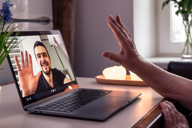 An old woman communicates with her son via video link through a laptop