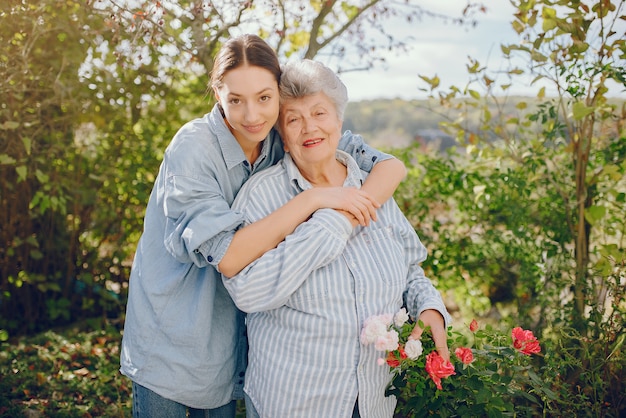 Старая женщина в саду с молодой внучкой