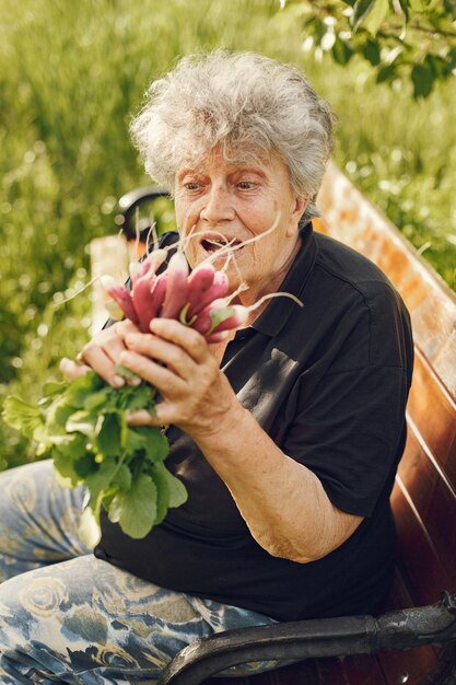 Old woman in a hat holding fresh radishes