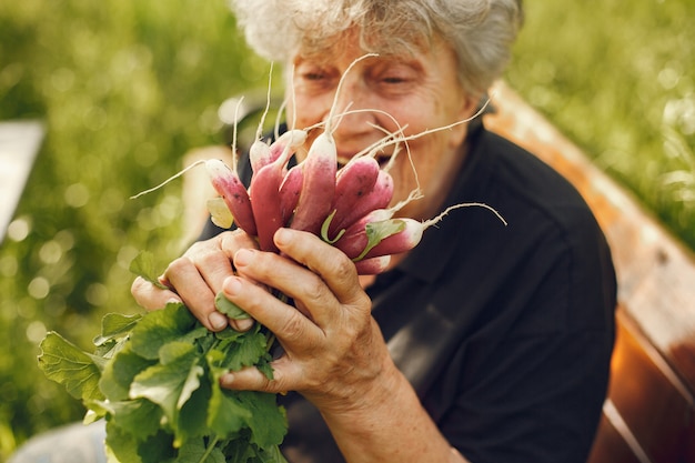 Vecchia donna in un cappello che tiene ravanelli freschi