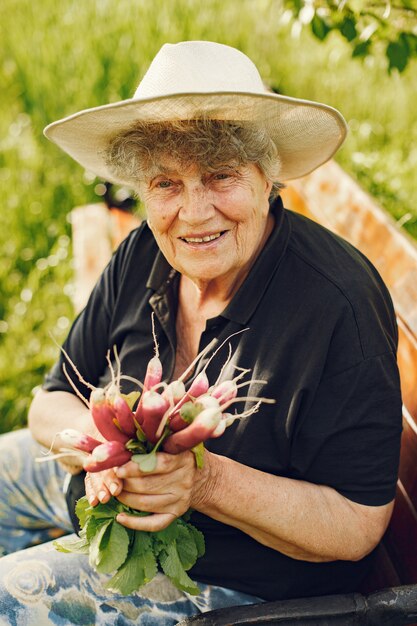 Old woman in a hat holding fresh radishes