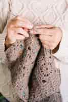 Free photo old woman in light sweater knitting scarf