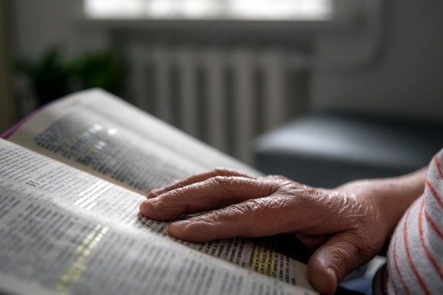 Una donna anziana legge le mani della bibbia da vicino